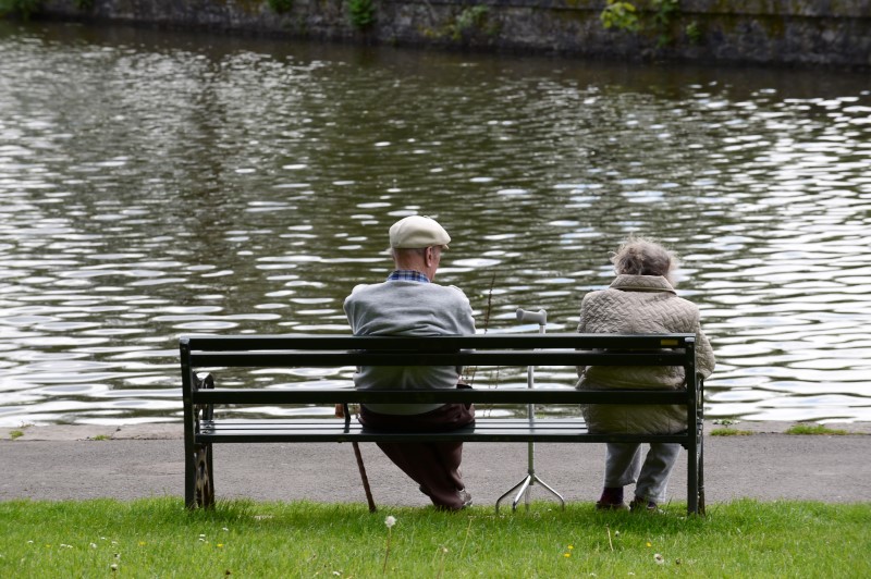 © Reuters. FILE PHOTO - Pensioners sit on a bench in a park, Merthyr Tydfil