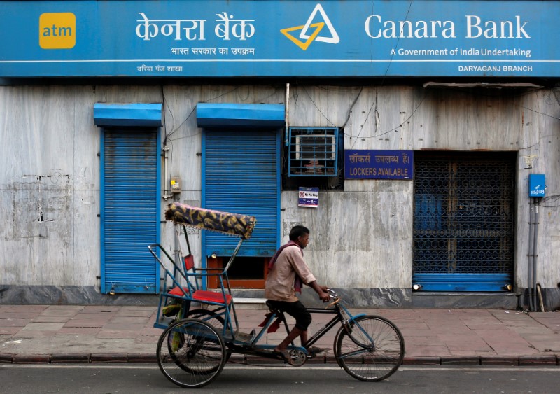 © Reuters. A rickshaw puller passes the Canara Bank branch in the old quarters of Delhi