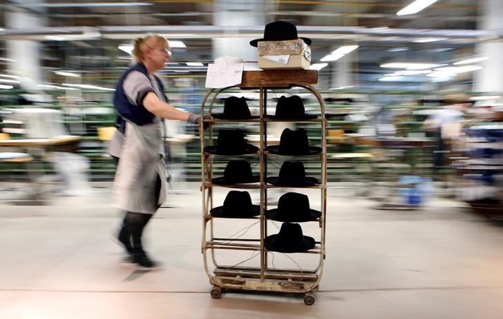 © Reuters. Una dipendente trasporta cappelli nella fabbrica Borsalino di Alessandria