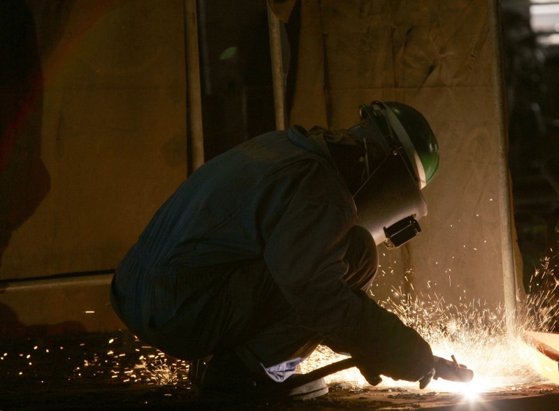 © Reuters. A worker welds steel plates at the Dubai Dry Docks workshop