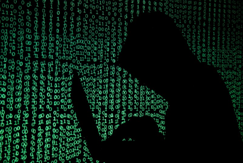 © Reuters. FILE PHOTO: Hooded man holds laptop computer as cyber code is projected on him in this illustration picture