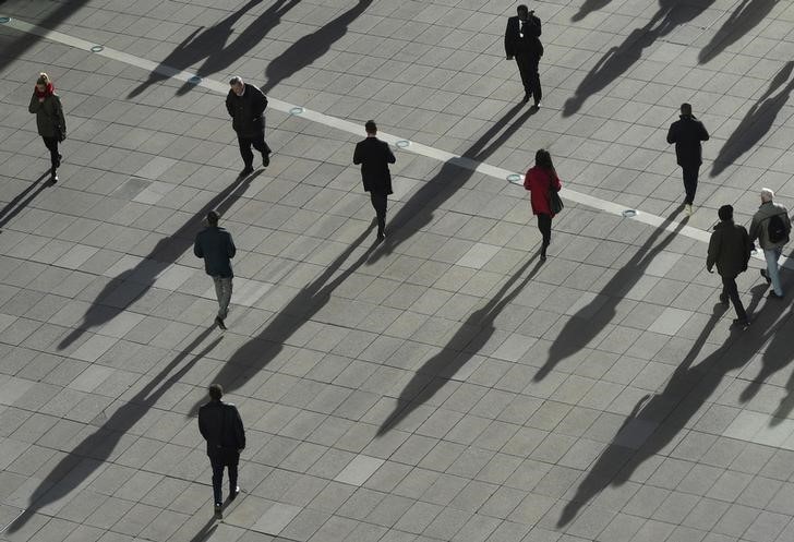 © Reuters. FILE PHOTO - People cast long shadows in the winter sunlight as they walk accross a plaza in the Canary Wharf financial district of London