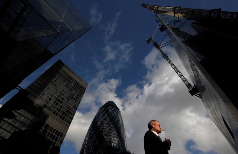 © Reuters. A worker walks past office skyscrapers in the City of London financial district, London, Britain