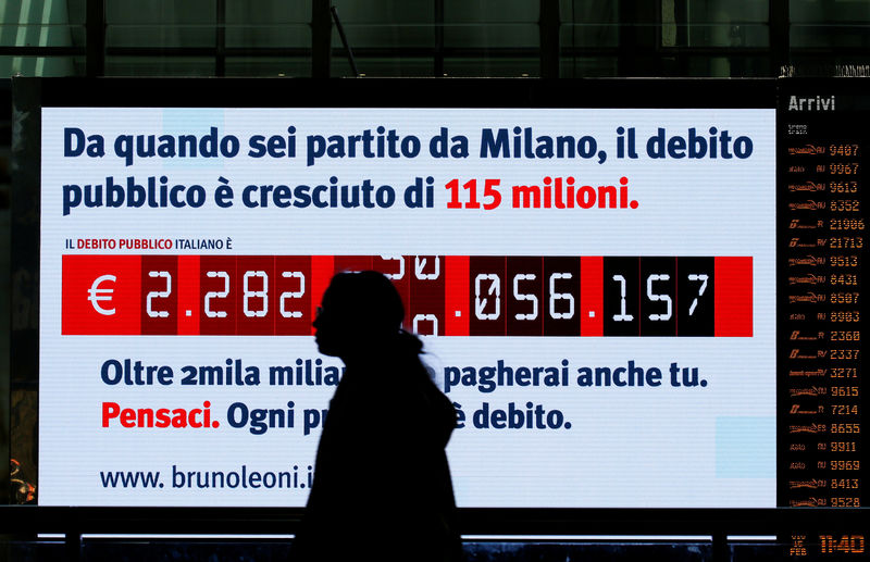 © Reuters. FILE PHOTO: Woman walks past a "debt clock" screen, installed by Bruno Leoni Institute's analysts, displaying Italy's public debt at the Termini central station in Rome