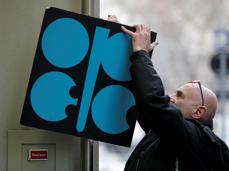 © Reuters. FILE PHOTO: A man fixes a sign with OPEC's logo next to its headquarter's entrance before a meeting of OPEC oil ministers in Vienna