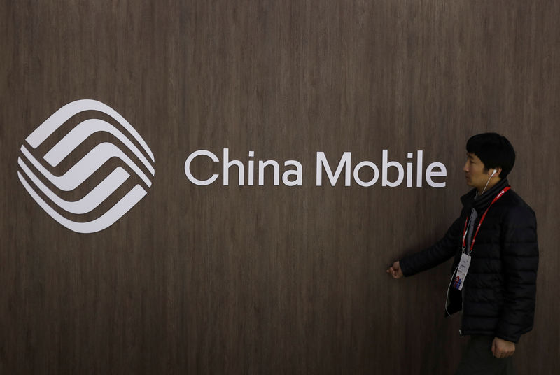 © Reuters. A man walks past the China Mobile logo at the Mobile World Congress in Barcelona