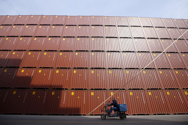 © Reuters. FILE PHOTO - A man rides a vehicle past containers at a port in Shanghai