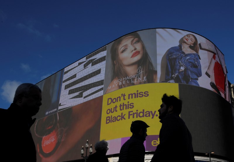 © Reuters. Shoppers are seen walking past the electronic billboard at Piccadilly Circus, showing retail adverts incuding one for 'Black Friday' in London, Britain