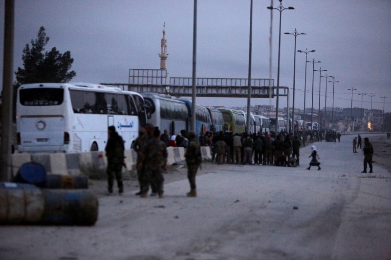 © Reuters. مسلحون من المعارضة السورية يغادرون بلدة بالغوطة في أول استسلام