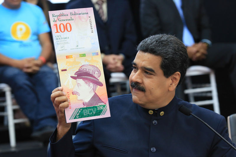 © Reuters. Venezuela's President Nicolas Maduro holds a sample of the new hundred bolivars note during a meeting with the ministers responsible for the economic sector at Miraflores Palace in Caracas