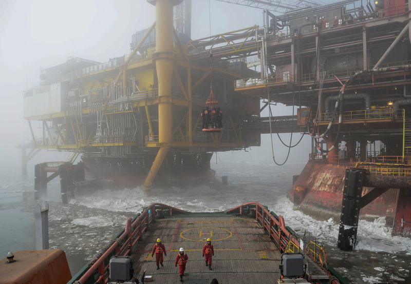 © Reuters. Workers are seen on an offshore oil platform in Liaodong bay off Liaoning