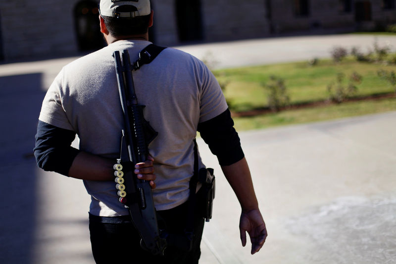 © Reuters. FILE PHOTO: A man walks with his Remington 870 Express 12 gauge shotgun during a pro-gun and Second Amendment protest in Phoenix