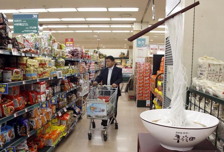 © Reuters. FILE PHOTO - People shop at a market in Seoul