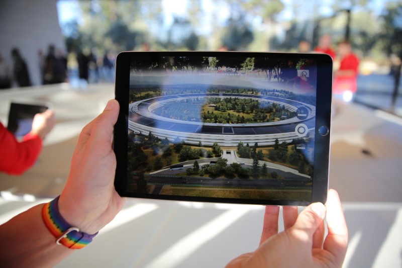© Reuters. FILE PHOTO - An Apple employee uses an iPad with an augmented reality app on it to show off features of the new Apple Park at the Apple Visitor Center in Cupertino