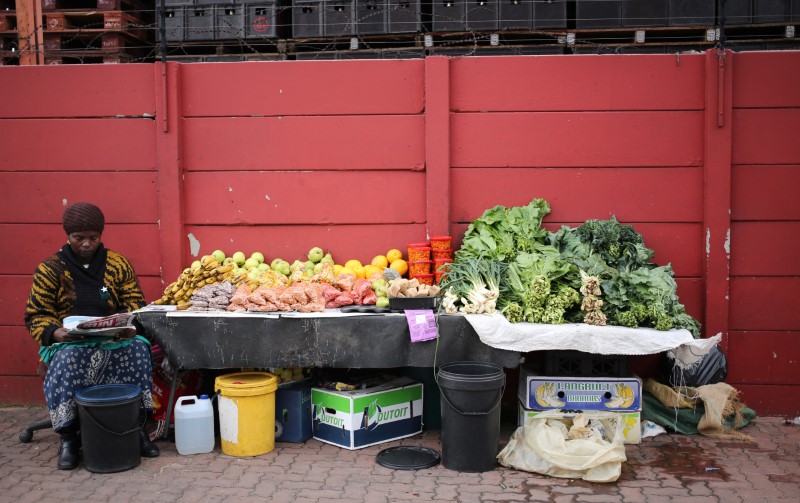 © Reuters. A street vendor waits for customers as she sits in front of her fruit and vegetabes stall in Johannesburg, South Africa