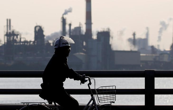 © Reuters. FILE PHOTO: A worker cycles near a factory at the Keihin industrial zone in Kawasaki, Japan