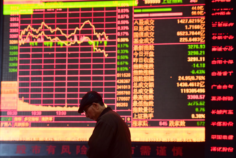 © Reuters. Man is seen against an electronic board showing stock information at a brokerage house in Fuyang