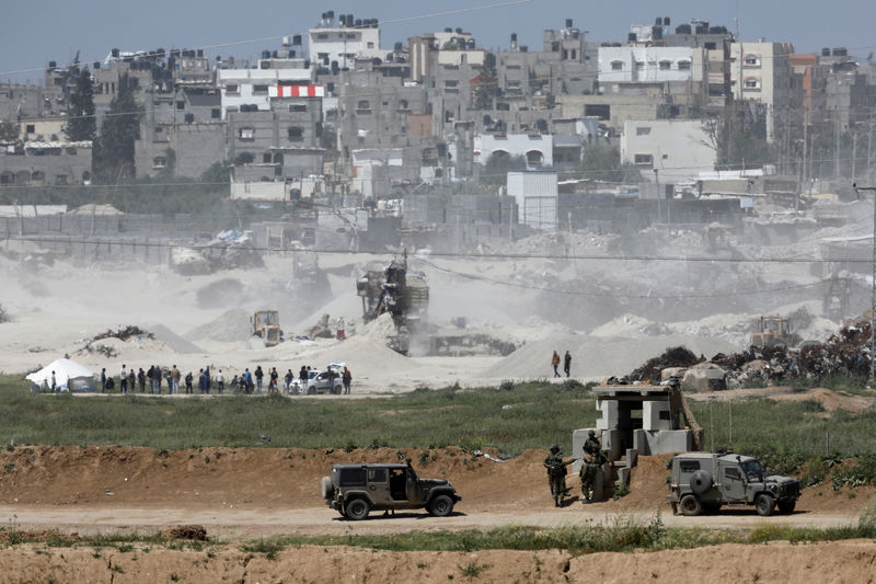 © Reuters. Israeli soldiers and military vehicles can be seen on the Israeli side of the border with the northern Gaza Strip, Israel