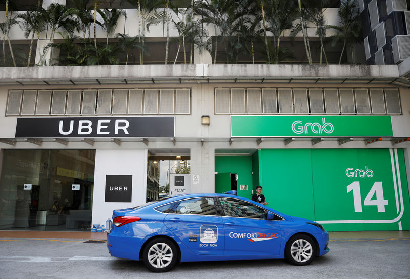 © Reuters. Um passa pelos escritórios do Uber e da Grab em Cingapura. 26/03/2018. REUTERS/Edgar Su