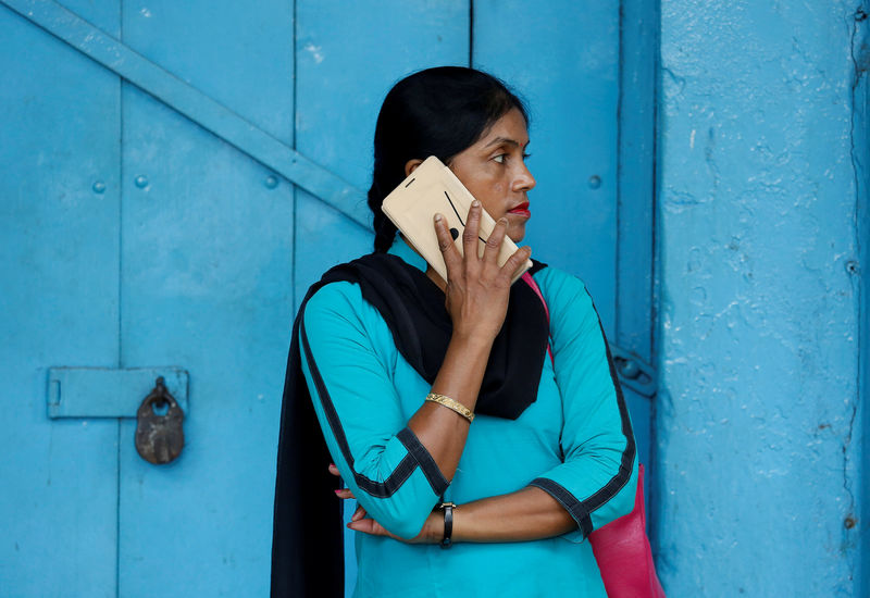 © Reuters. FILE PHOTO: A woman talks on her mobile phone on a pavement in Kolkata