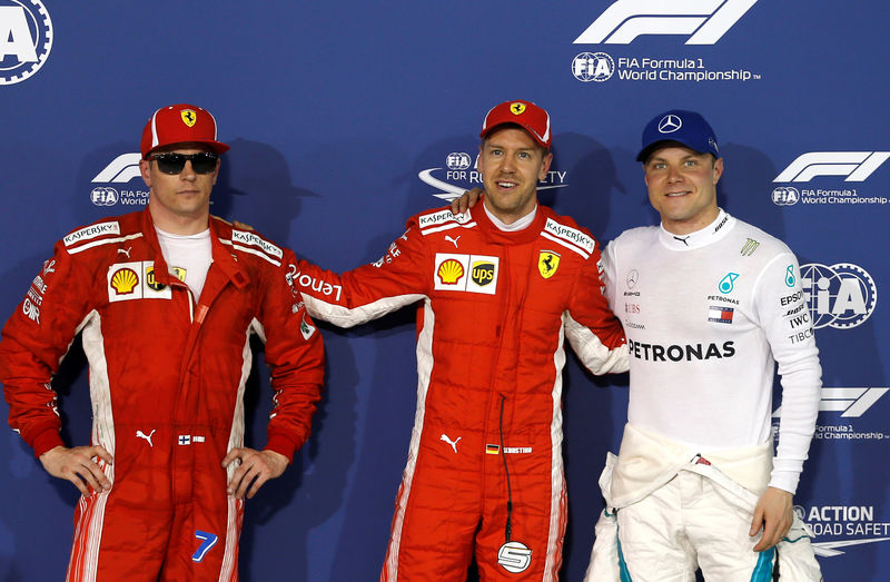 © Reuters. El piloto de Ferrari Sebastian Vettel celebra la "pole position" con su compañero de equipo Kimi Raikkonen y con el piloto de Mercedes Valtteri Bottas, tras la clasificación para el Gran Premio de Bahréin