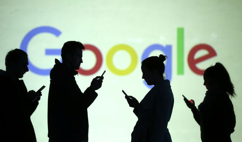 © Reuters. Silhouettes of mobile users are seen next to a screen projection of Google logo in this picture illustration