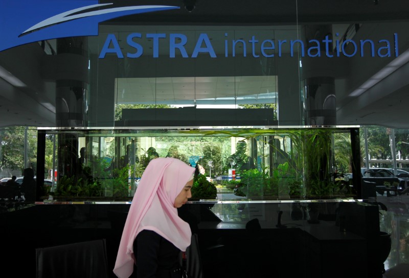 © Reuters. FILE PHOTO - A woman walks near a logo of PT Astra International at Astra International headquarter in Jakarta