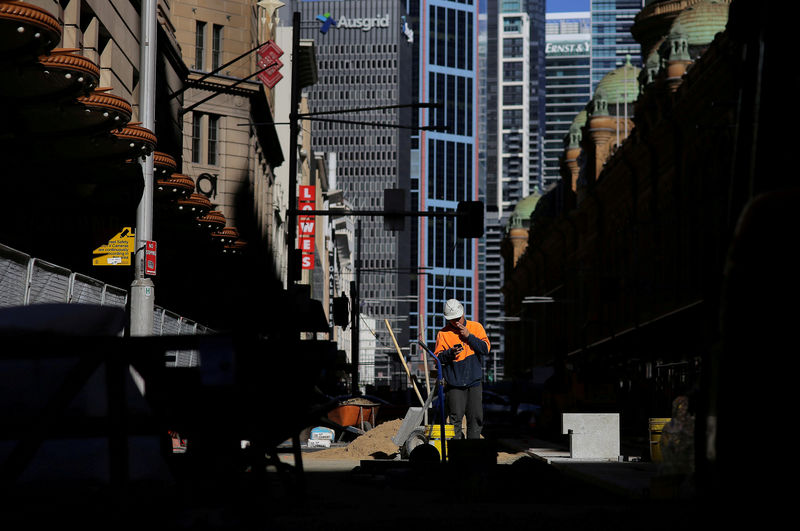© Reuters. FILE PHOTO: A construction worker smokes a cigarette as he looks at his mobile phone on a worksite in Sydney