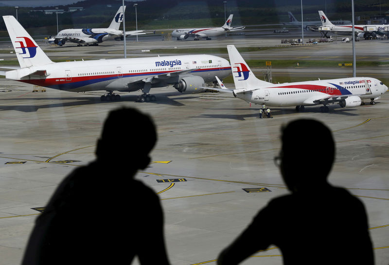 © Reuters. FILE PHOTO: Men watch Malaysia Airlines aircraft at Kuala Lumpur International Airport in Sepang, Malaysia