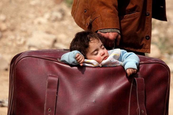 © Reuters. Criança dorme dentro de mala no vilarejo de Beit Sawa, em Ghouta Oriental