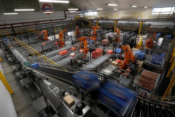 © Reuters. FILE PHOTO - Robotic arms load biscuits onto pallets on the production line of Pladis' McVities factory in London