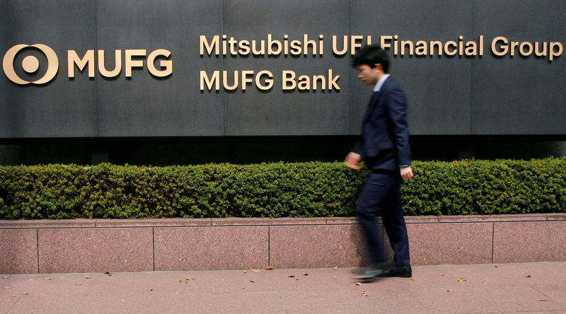 © Reuters. FILE PHOTO: A man walks past a signboard of Mitsubishi UFJ Financial Group and MUFG Bank at its headquarters in Tokyo
