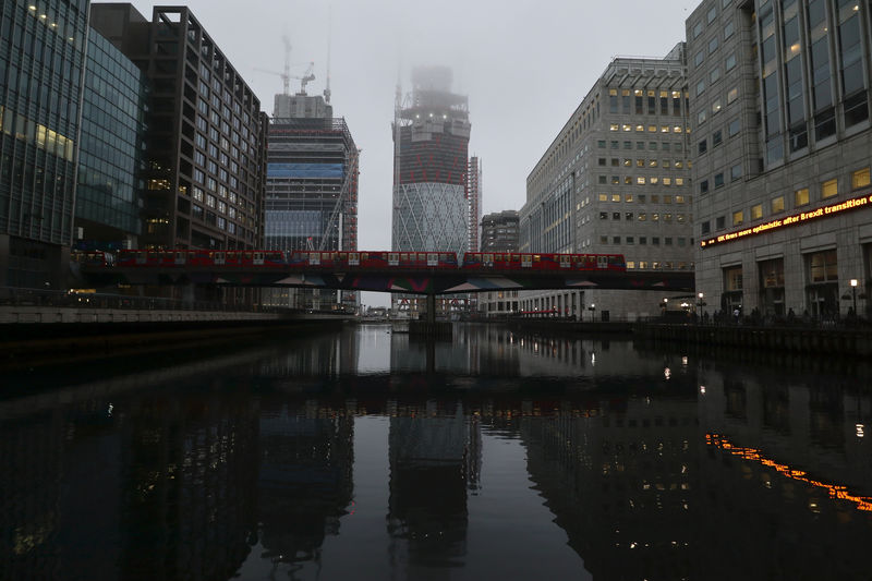 © Reuters. A DLR train crosses a bridge in front of construction work in the early morning mist in London's Canary Wharf financial district, London