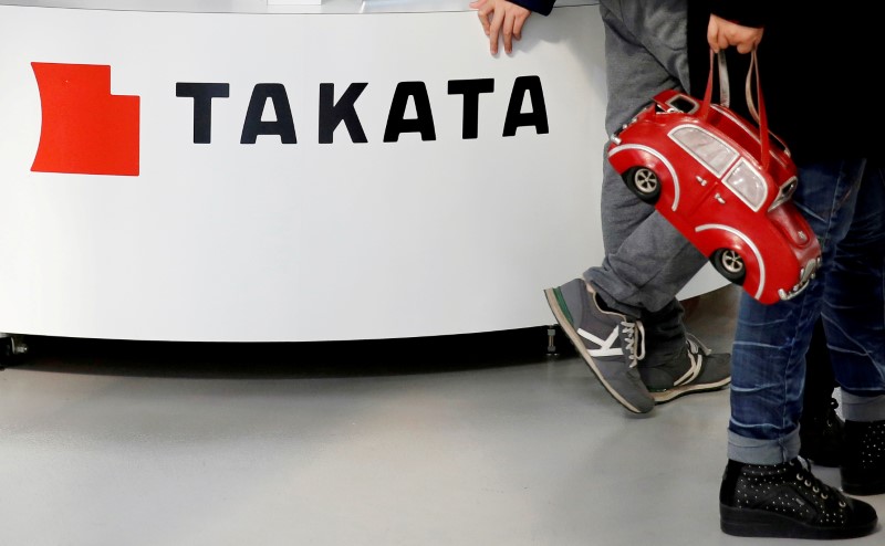 © Reuters. FILE PHOTO: Visitors walk past a logo of Takata Corp on its display at a showroom for vehicles in Tokyo, Japan