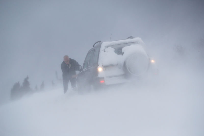 © Reuters. A man digs a Landrover out of a snow drift in Coalville