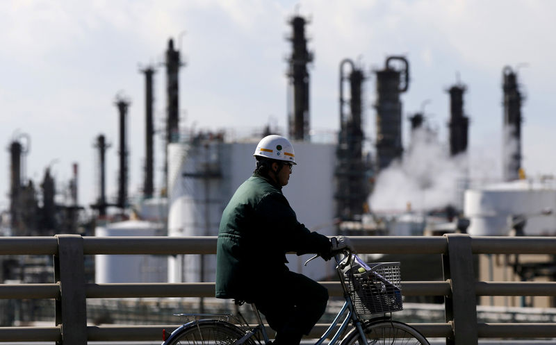 © Reuters. FILE PHOTO -  A worker cycles near a factory at the Keihin industrial zone in Kawasaki, Japan