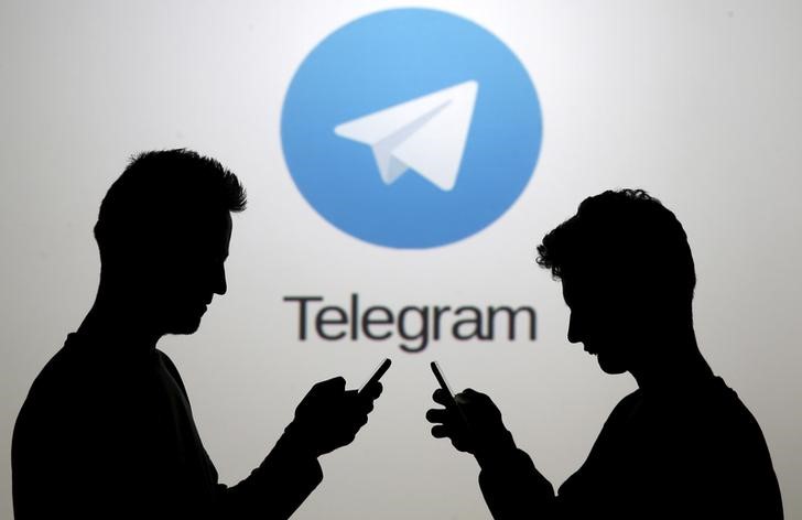 © Reuters. Two men pose with smartphones in front of a screen showing the Telegram logo in this picture illustration taken in Zenica