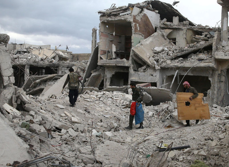 © Reuters. Personas caminando sobre edificios en ruinas en la ciudad de Duma