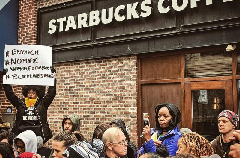 © Reuters. Tsehaitu Abye holds up a banner as people demonstrate outside a Starbucks cafe in Philadelphia outside a Starbucks cafe in Philadelphia