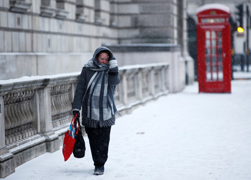 © Reuters. A woman walks through the snow storm in central London
