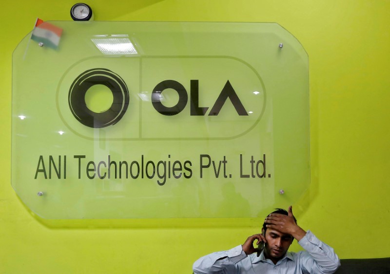 © Reuters. FILE PHOTO: An employee speaks over his phone as he sits at the front desk inside the office of Ola cab service in Gurugram