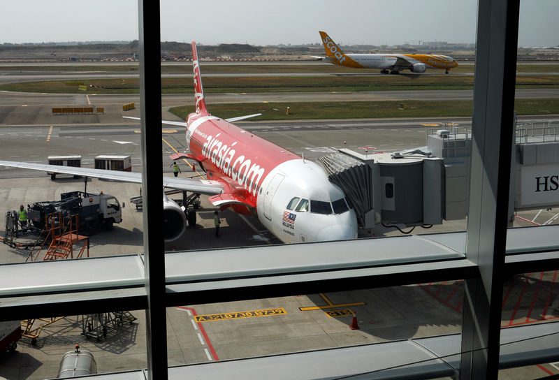 © Reuters. A Scoot airplane takes off past an Airasia airplane at Changi Airport Terminal 4 in Singapore