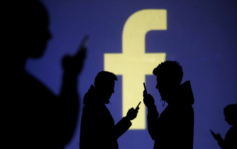 © Reuters. Silhouettes of mobile users are seen next to a screen projection of Facebook logo in this picture illustration