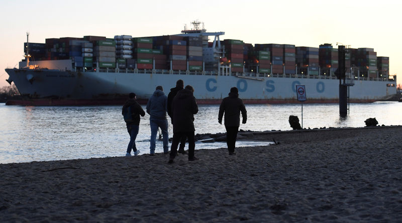 © Reuters. FILE PHOTO: People enjoy the sunset in front of a container ship at the Elbe river in Hamburg
