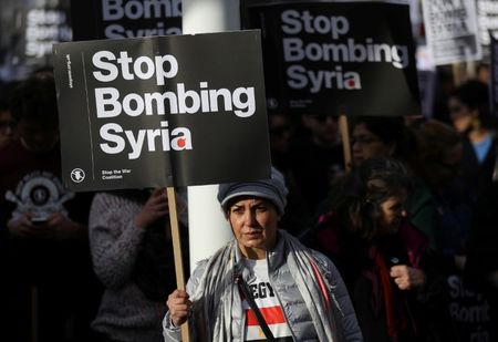 © Reuters. Protesters hold placards during a demonstration against bombing Syria outside the Houses of Parliament in London