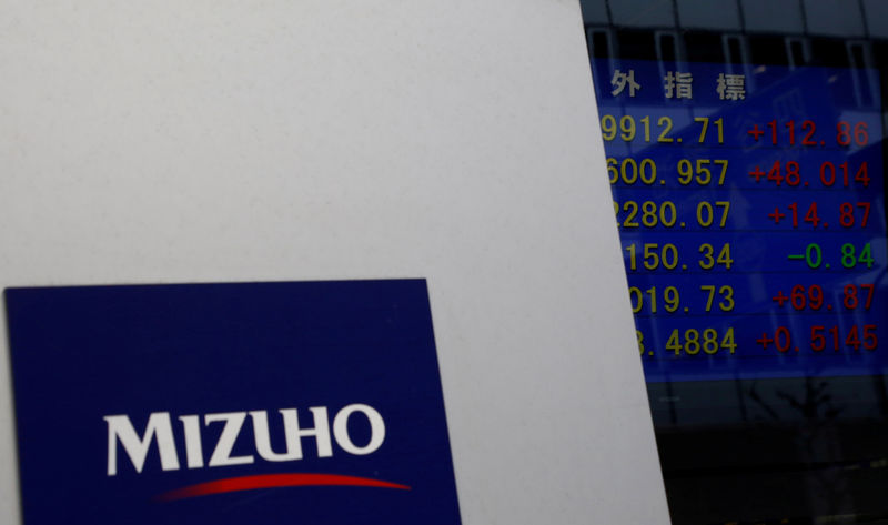 © Reuters. FILE PHOTO: Mizuho Financial Group's logo is seen next to an electronic board showing stock prices indexes at a branch of Mizuho Securities in Tokyo