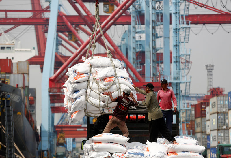 © Reuters. Workers help unload bags of rice from a cargo ship on to a truck at Tanjung Priok Port in Jakarta,