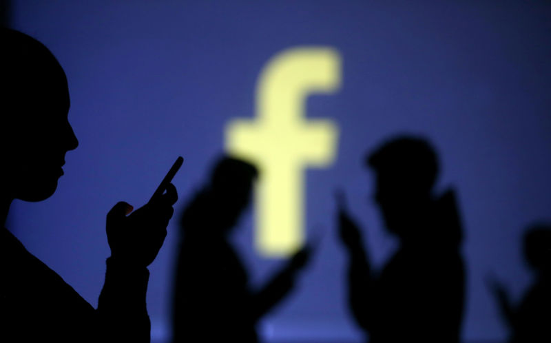 © Reuters. Silhouettes of mobile users are seen next to a screen projection of Facebook logo in this picture illustration