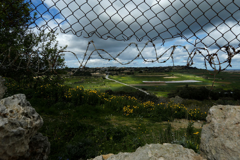 © Reuters. Hole in the fence leading to the lookout point used by one of the three men accused of the assassination of anti-corruption journalist Daphne Caruana Galizia, is seen in Bidnija