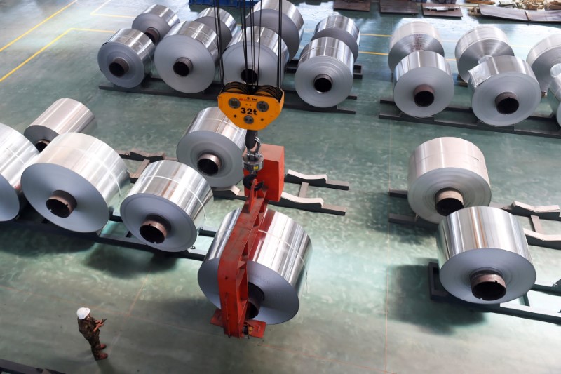 © Reuters. An employee looks at an aluminium foil roll being lifted at a plant in Binzhou